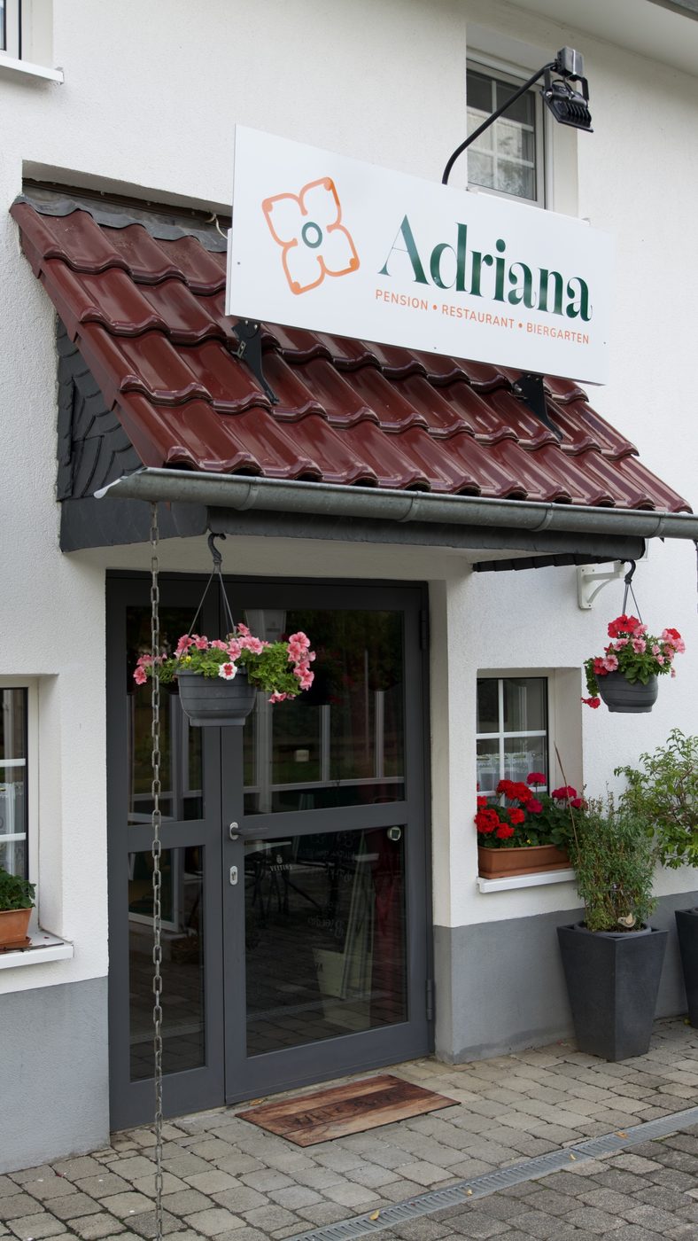 Der Eingang mit dem Schild „Adriana“ und Geranien